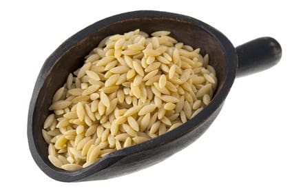 scoop of orzo pasta (rosa marina) orzo (rosa marina), a rice shaped pasta made of wheat semolina on a rustic wooden scoop isolated on white